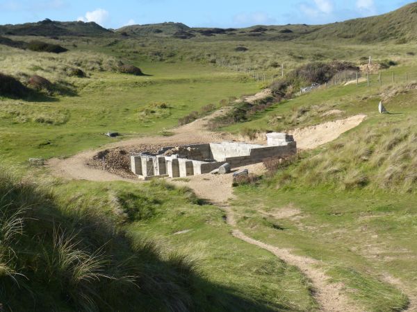 Tweede kluizenarij, onlangs onder het zand vandaan gekomen en afgeschermd met gemetselde muur. 'Sanctus Piranus in Zabulo' (Sint Piran in het Zand'.