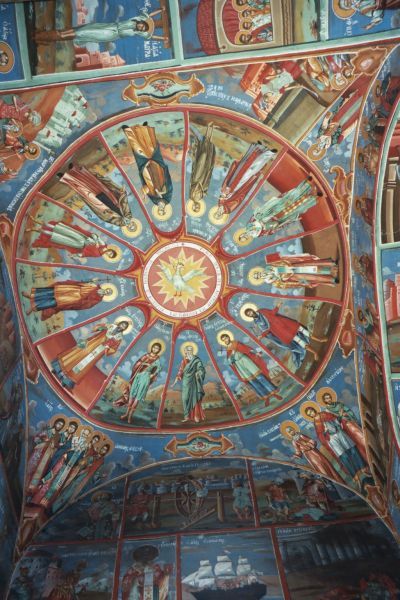 In de koepel staan de heiligen afgebeeld van 1 t/m 13 april, volgens de Grieks-Orthodoxe kalender. Te beginnen bij het tweetal boven de kop van de duif die de Heilige Geest symboliseert. Opm.: hieronder geldt steeds: 'rechts' = 'tegen de klok in'. Dat zijn rechts Elisabeth van Egypte (1 april; volgens de Romeinse kalender 2 april: † 5e eeuw) en links haar geestelijk leidsman Zosimas (4 april: † 5e eeuw). Rechts van Elisabeth staat Titus de Wonderdoener (2 april: † 9e eeuw); rechts van Titus: Nicetas de Belijder (3 april: † 824). Op 4 april behoorde eigenlijk Zosimas te staan, maar omdat hij al is afgebeeld bij Maria van Egypte wordt hij nu overgeslagen. Rechts van Nicetas: links de martelaar Theodulus, rechts Agathapodus (5 april: † 303). Rechts van deze twee: Eutychius van Constantinopel (6 april: † 582). Rechts van Eutychius (onder de pootjes van de duif): Calliopus van Pompeiopolis (7 april: † 303). Rechts van Calliopus: Herodion van Patras (8 april: † 1e eeuw); rechts van Herodion: Eupsychius van Cesarea (9 april: † 362). Rechts van Eupsychius: Terentius van Cartjago (10 april: † 250); rechts van Terentius: Antipas van Pergamum (11 april: † 90). Rechts van Antipas (dus links van Maria en Zosimas): Basilius van Parium (12 april: † 750). In de hoek links onder Maria en Zosimas: Maximus Durostorum en Quinctillianus (13 april: † 303). In de andere hoek: rechtsonder: (waarschijnlijk) de marteldood van Simeon van Seleucië (21 april: † 341). In de hoek daartegenover over de diagonaal: links Elisabeth de Wonderdoenster (24 april: † 540) en rechts daarvan Pasicrates van Durostorum en Valentinus (24 april: † 228). De afbeelding in de vierde hoek is niet goed thuis te brengen. Verder onder Titus de Wonderdoener: de gekruisigde Maura van Antinoë (3 mei: † 298). 18e (?) eeuw, koepelbeschildering.