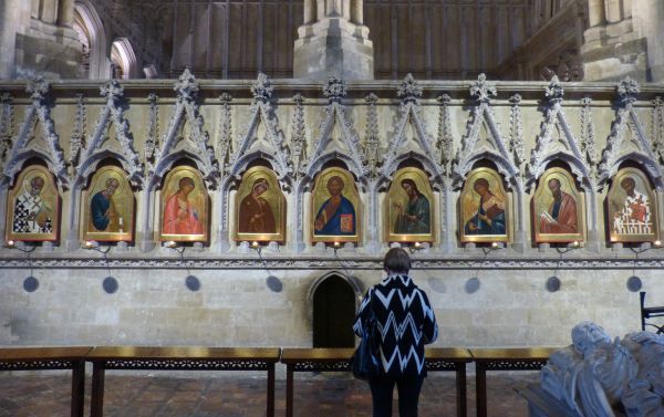 Op de achtergrond, onder de heiligengalerij: voormalig doorkruipgat (The Holy Hole) naar de reliekencrypte van Swithun. Rond de ingang zijn de stenen zwart geworden van de handen die er - llichtjes steun zoekend - bij het binnengaan.