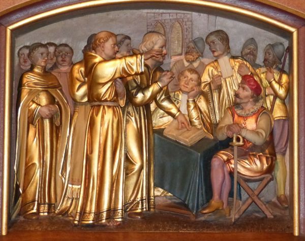 Het debat op de vooravond van de terechtstelling van de Negentien Martelaren van Gorkum. Op de voorgrond een franciscaan met gestrekte arm: moet Nicolaas Pieck zijn. Half zichtbaar achter hem: Lenaert van Vechel, enigszins voorovergebogen, met de hand op de Bijbel. Op de voorgrond rechts, met rode muts, Lumey, leunend op zijn zwaard. Naast hem gezeten een een aandachtig luisteraar. Achter die twee Andries Cornelissen van de nieuwe leer, herkenbaar aan zijn domineesbef.