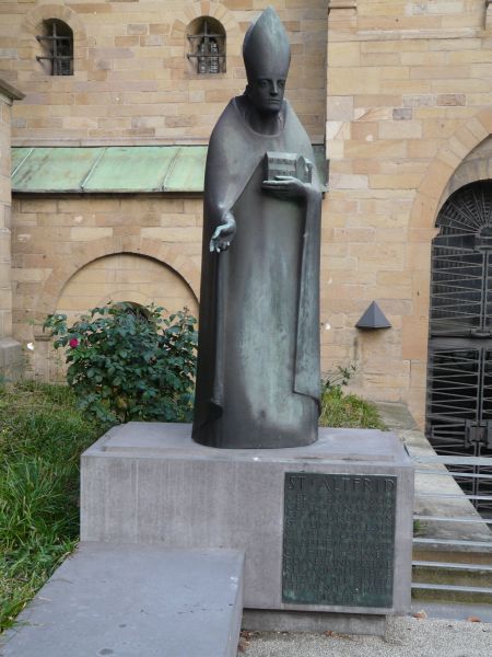 Altfried voor de kathedraal van Essen. Bijschrift luidt: 'St.Altfrid Geboren rond 800; gestorven 15.8.874; vierde bisschop van Hildesheim; bouwer van de dom in Hildesheim en van de abdij in Essen; bijgezet in de crypte van de Essener abdijkerk. ca 2000, sculptuur; Duitsland, Essen, kathedraal.