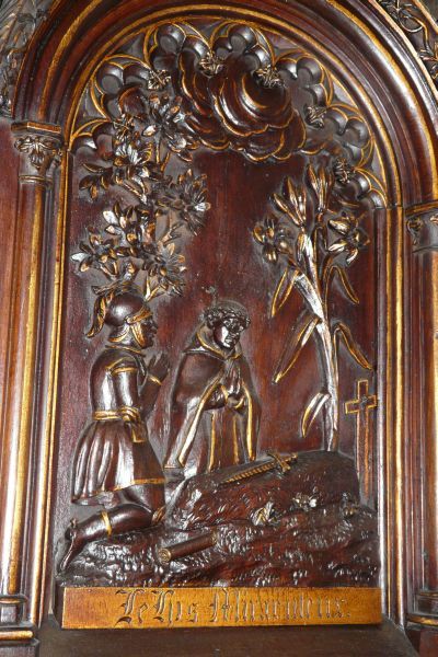 ± 1900, houtrelíëf, preekstoel. Uit de mond van dedode Salaün bloeit een Ave-Marialelie.