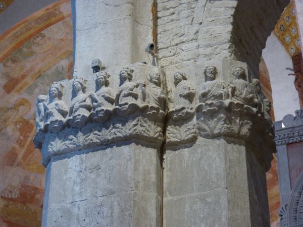 Hoog in de kapitelen vóór in de kerk een aantal heiligen onder wie de vier martelaressen met kroon en palmtak. Vandaar kijken zij neer op de gelovigen beneden; kunnen de gelovigen naar hen opzien.