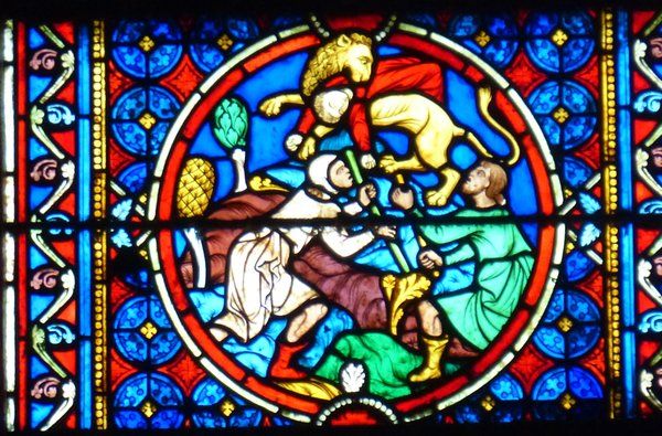 Het ene zoontje wordt uit de muil van de leeuw gered door dorpelingen. 13e/19e eeuw, glasschilderkunst.