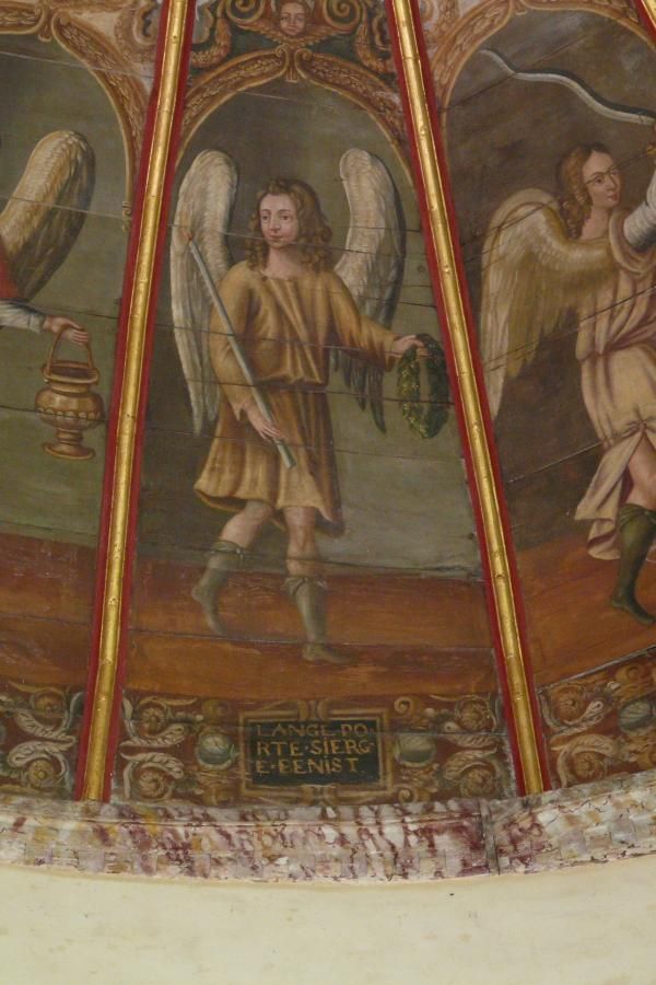 'De engel met gewijde kaars' 'L'ange porte sierge benist [cierge bénit]' (de engel draagt een gewijde kaars) Daarnaast heeft hij een lauwerkrans in de handen, de krans van de overwinning. Die geeft hij ons, als wij een gewijde kaars opsteken. De kaars draagt hij naar de hemel tot voor Gods troon.