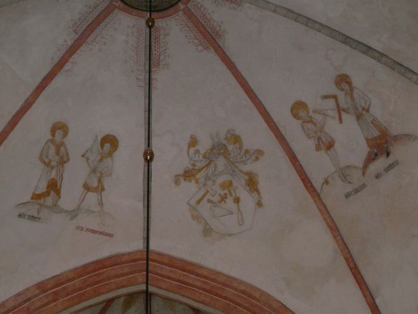 Hoewel ter plaatse aangeduid met de naam 'Vier Gekroonden' gaat het in feite om vier van de vijf beeldsnijders: v.l.n.r. Castorius, Sempronianus, Claudius en Nicostratus. De vijfde Simplicius ontbreekt. Zij waren patroonheiligen van handwerkslieden, metselaars, timmerlieden, bouwarbeiders enz. Vandaar dat tussen hen in een wapen is afgebeeld met de attributen van handwerkslieden: beitel, troffel, steenboor, steenhamer. Castorius draagt een steekbeitel, Sempronianus een troffel, Claudius een passer en Nicostartus een winkelhaak.