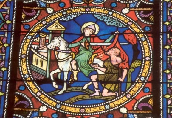 Glasschilderkunst Martinus schenkt de helft van zijn mantel aan een arme. Dit tafereel is in de kunstgeschiedenis honderden keren afgebeeld. Meestal zit Martinus op een paard (hetverhaal zegt daar niets over). Het is bovendien historisch onjuist, want Martinus zou pas enkele jaren later ingedeeld worden bij de cavalerie. Effect is wel dat hij hoog te paard zit, verheen boven de arme. Ondanks die positie heeft hij oog voor de 'mindere'. Daarin lijkt hij op Jezus van wie wordt gezegd: 'Hij die de gestalte van God had, hield zijn gelijkheid aan God niet vast, maar deed er afstand van...'(Filippenzen 2,6).
