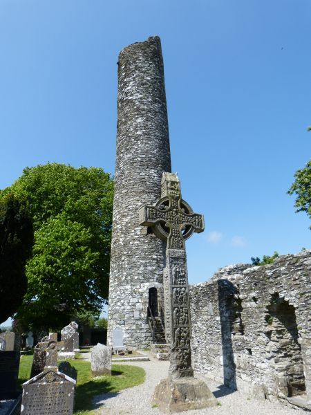 Indrukwekkende ruïnes van Monasterboice. Op de voorgrond één van de zogeheten hoogkruisen met Bijbelse scènes in reliëf gebeeldhouwd. Op de achtergrond restant van een ronde toren uit de 9e of 10e eeuw, bestemd als uitkijkpost, voor voedselopslag en als veilig heenkomen in tijden van gevaar.